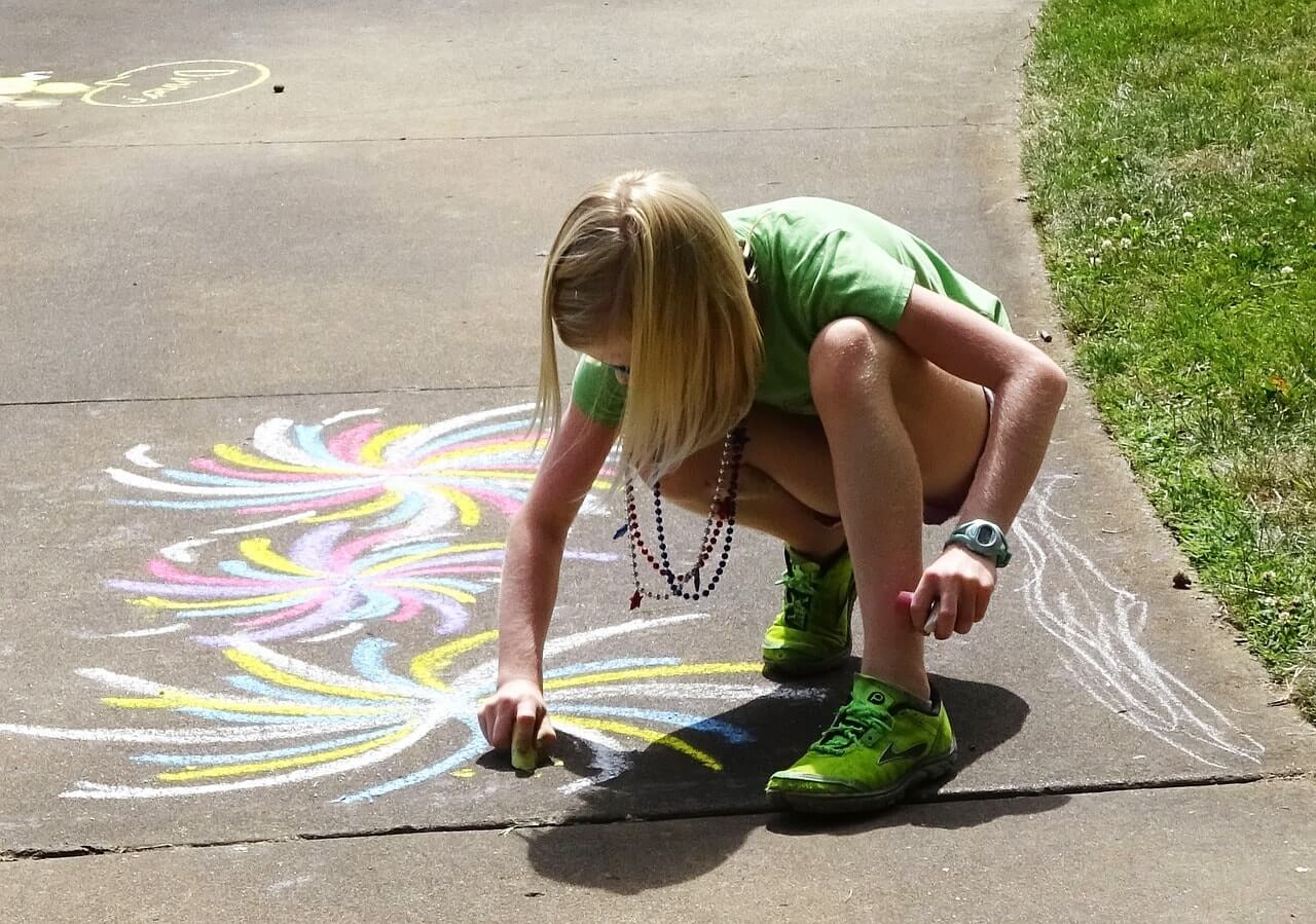 Девочка рисует на асфальте
