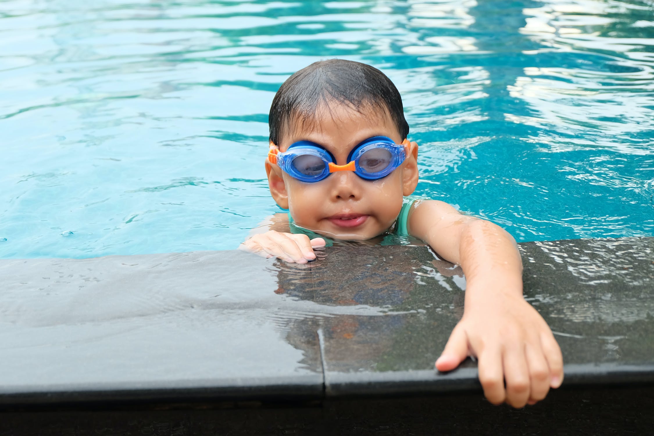 Мальчик купается в бассейне